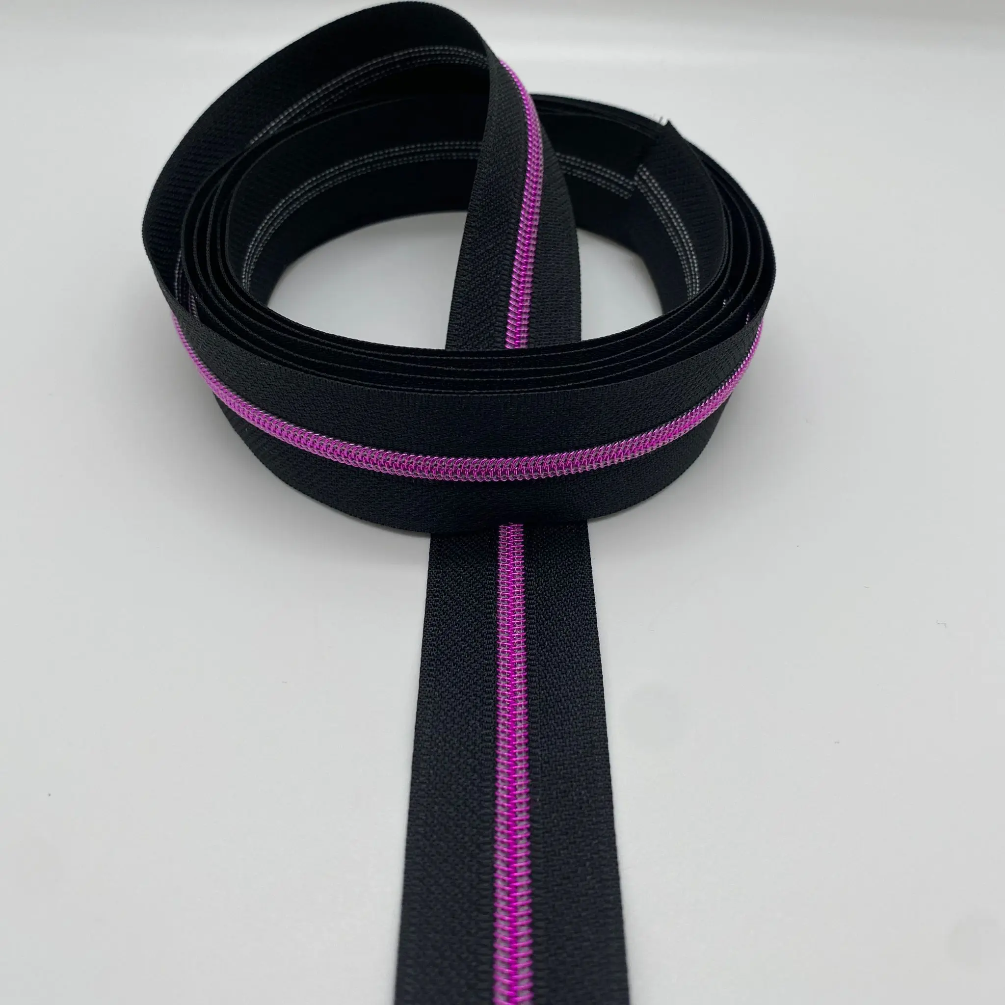 Reißverschluss Intense Colors Pink Schwarz als Endlosreißverschluss mit schwarzem Band und pinkfarbener metallisierter Spiralraupe für schmale Zipper.