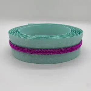 Aufgerollter Reißverschluss Intense Colors Pink Mint mit mintfarbenem Band und metallisierter pinker Spiralraupe. Breiter Endlosreißverschluss als Meterware für Taschen und kreative DIY-Projekte.