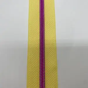Detailaufnahme des Reißverschlusses Intense Colors Pink – Sunny Yellow schmal mit glänzender metallisierter pinkfarbener Spiralraupe auf sonnengelbem Reißverschlussband.