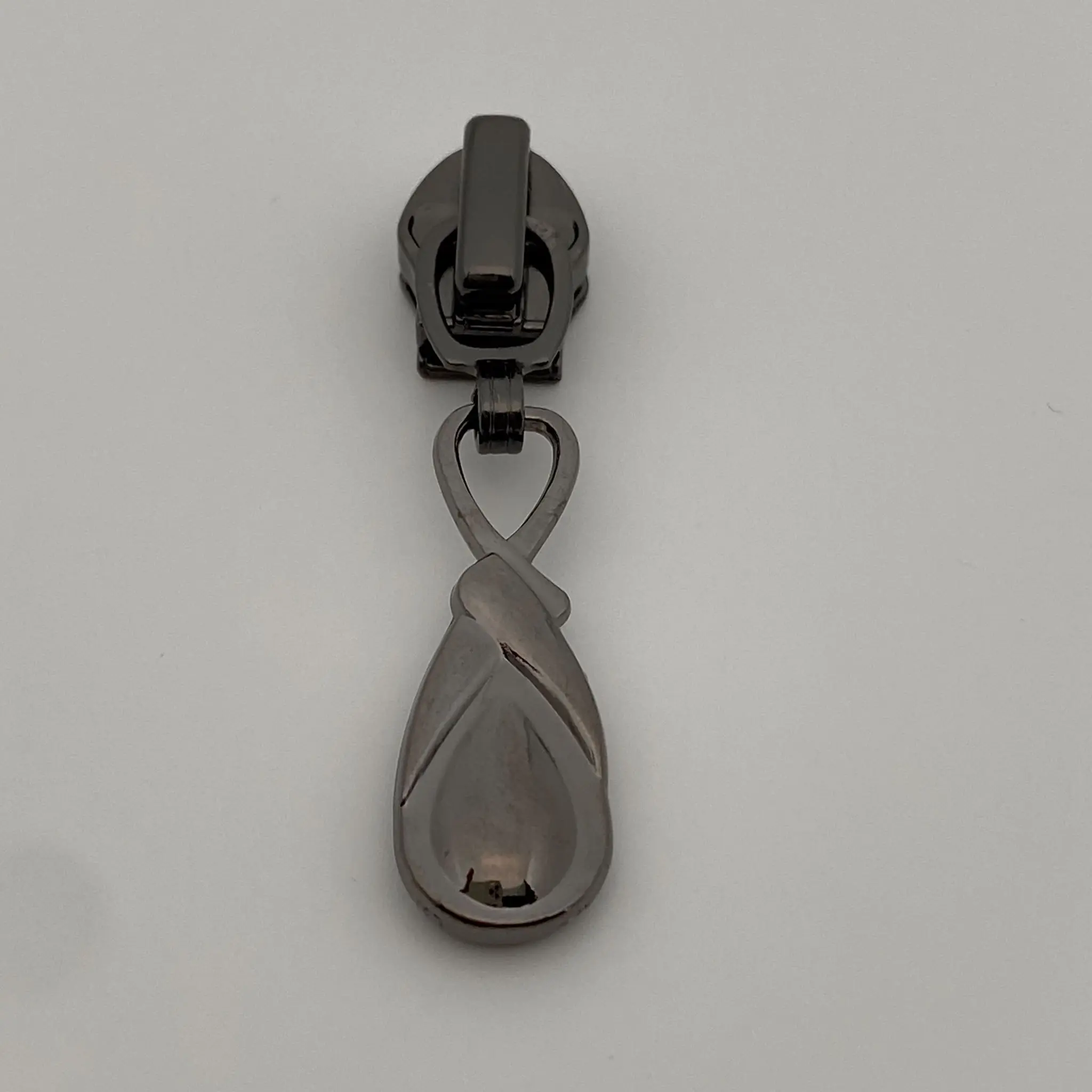 Zipper Infinity Gunmetal für 6,5 mm breite Spiralreißverschlüsse – Vorderansicht des hochwertigen Reißverschluss-Schiebers mit elegantem Anhänger im Infinity-Design und Autolock-Funktion.
