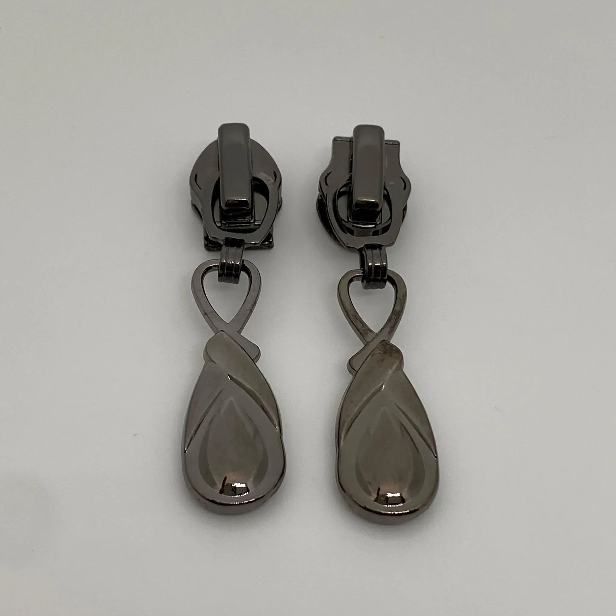 Zipper Infinity Gunmetal für 6,5 mm breite Spiralreißverschlüsse – Vorder- und Rückansicht des hochwertigen Reißverschluss-Schiebers mit Infinity-Anhänger und integrierter Autolock-Funktion.
