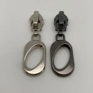Zipper Eclipse für 6,5 mm breite Spiralreißverschlüsse in den Farben Silber und Gunmetal – hochwertiger Metall-Zipper mit ovalem Anhänger und Autolock-Funktion.