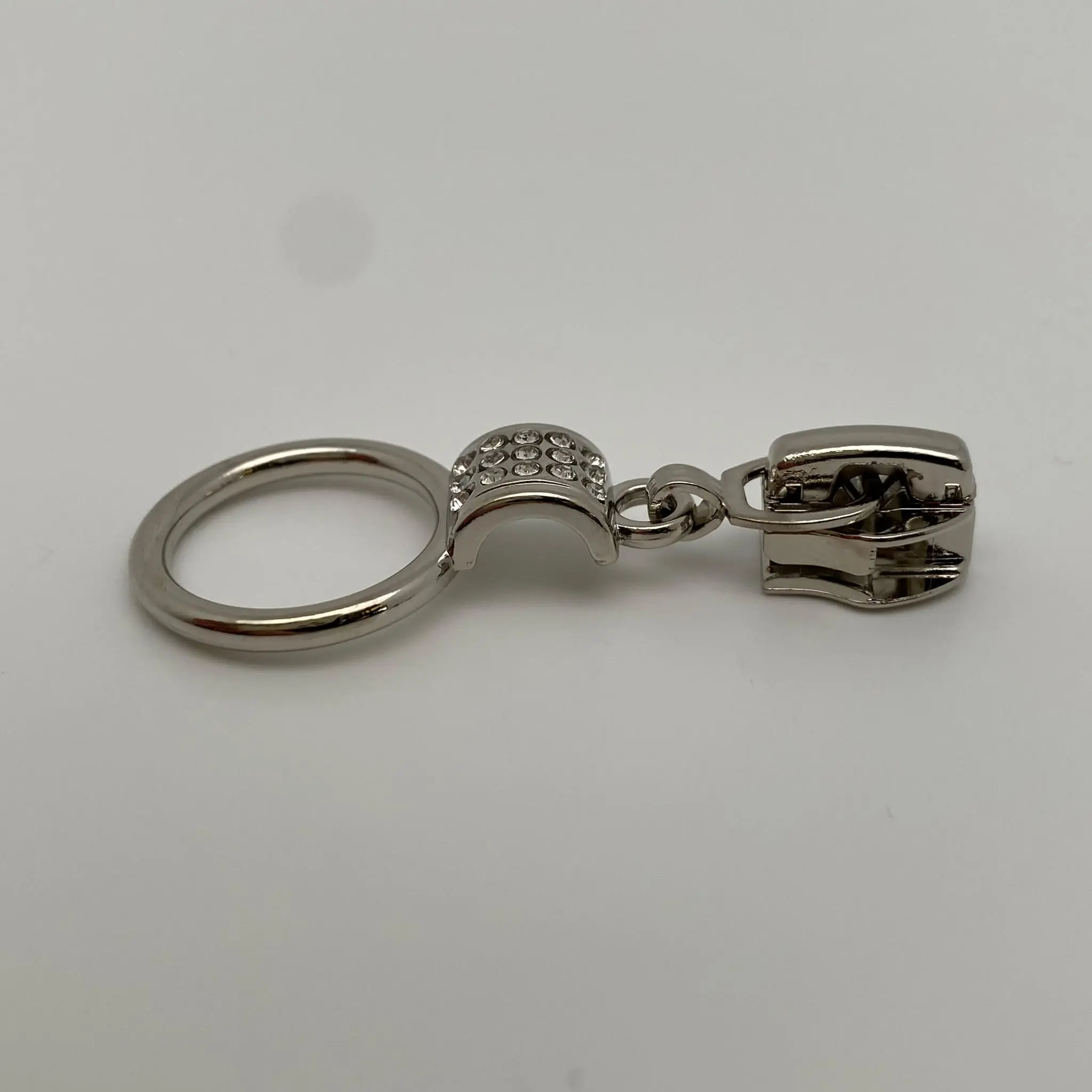 Seitenansicht des Zipper Crystal Loop in Silber mit Ring-Anhänger, dekorativen Kristallsteinen und Autolock-Funktion für 6,5 mm breite Spiralreißverschlüsse.
