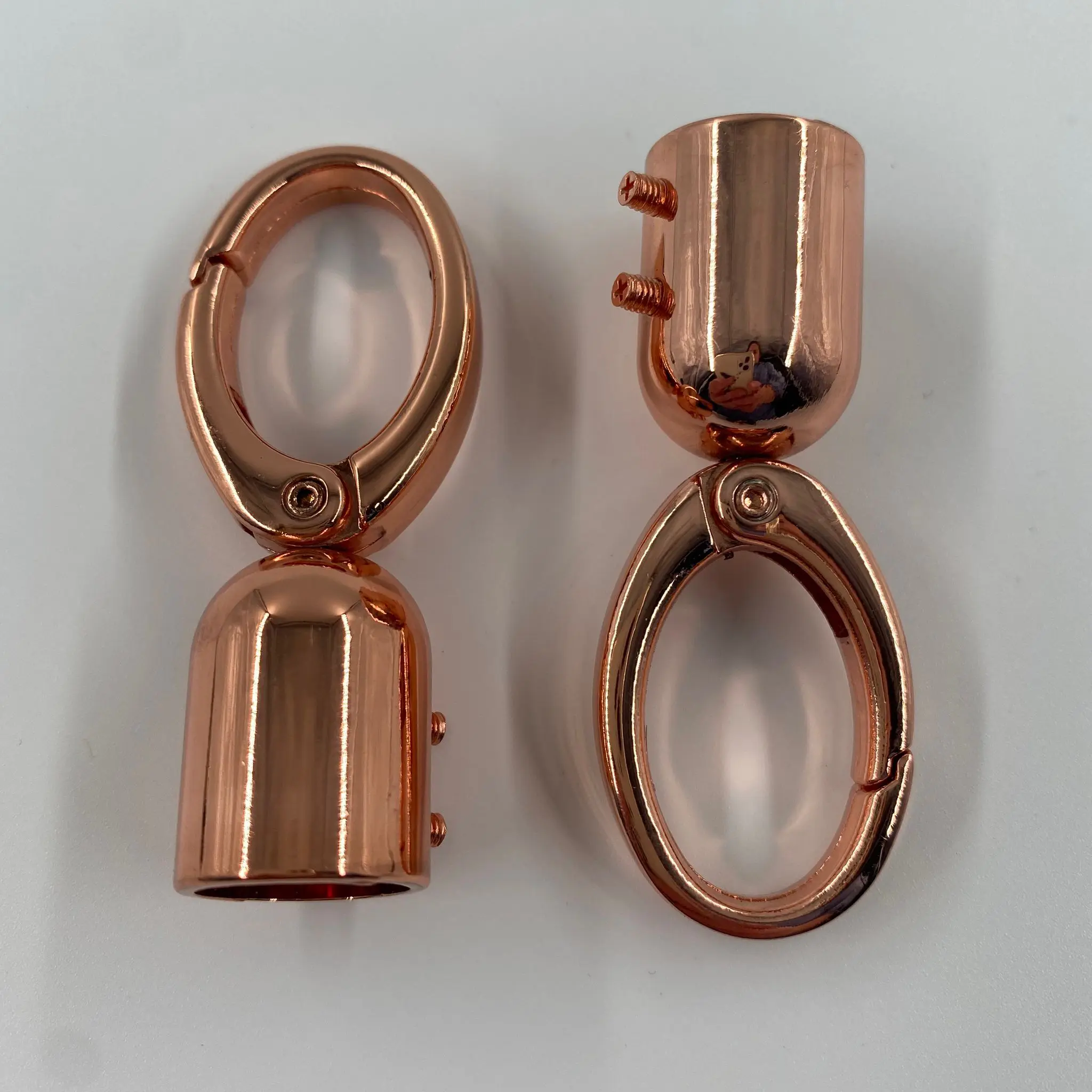 Zwei Kordelkarabiner in Roségold mit ovalem Karabiner, rundem Kordel-Endstück und seitlichen Befestigungsschrauben für individuelle Taschengurte.