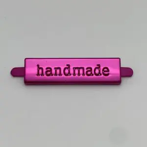 Metalllabel Handmade Pink in der Vorderansicht mit eingeprägtem Schriftzug und glänzender Metalloberfläche