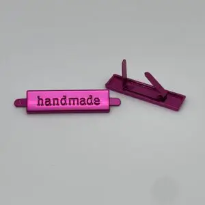 Metalllabel Handmade Pink von vorne und hinten mit zwei sichtbaren Befestigungslaschen auf der Rückseite