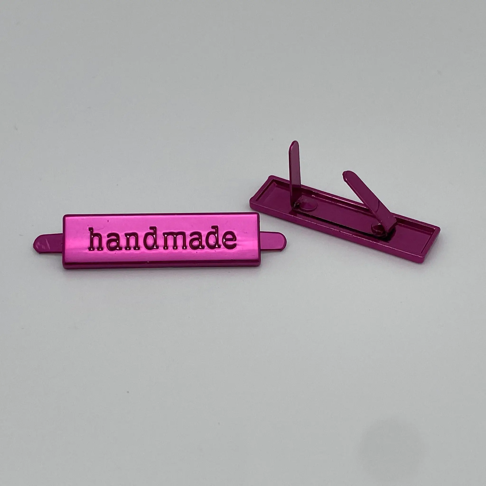 Metalllabel Handmade Pink von vorne und hinten mit zwei sichtbaren Befestigungslaschen auf der Rückseite