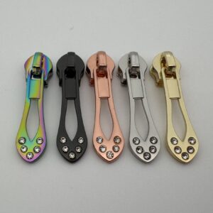 Fünf Zipper Luxury mit Strass für 6,5 mm Spiralreißverschlüsse in den Farben Regenbogen, Gunmetal, Roségold, Silber und Gold – hochwertige Premium-Reißverschluss-Schieber in eleganter Tropfenform für Taschen, Geldbörsen, Rucksäcke und exklusive Handmade-Projekte.