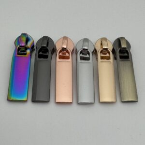 Zipper Edge für breite 6,5 mm Spiralreißverschlüsse in sechs Farben – Regenbogen, Gunmetal, Roségold, Silber, Hellgold und Altmessing. Moderne Premium-Reißverschluss-Schieber mit geradlinigem Design für Taschen, Geldbörsen und Handmade-Projekte.